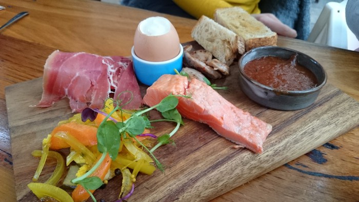 Breakfast board of smoked ocean trout, house pork sausage, serrano ham, pickles and a soft boiled egg with rye soldiers